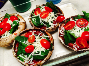 Delicious mushroom caps with tomato sauce, spinach and grape tomatoes topped with mozzarella cheese.